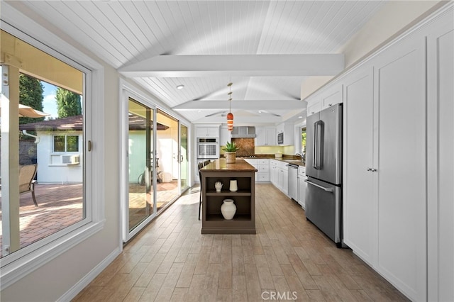 kitchen with wooden counters, white cabinetry, vaulted ceiling with beams, stainless steel appliances, and a center island