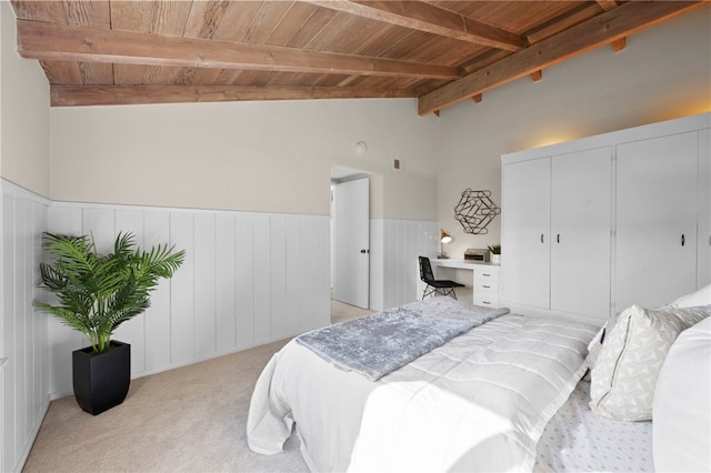 bedroom with lofted ceiling with beams, built in desk, light carpet, and wood ceiling