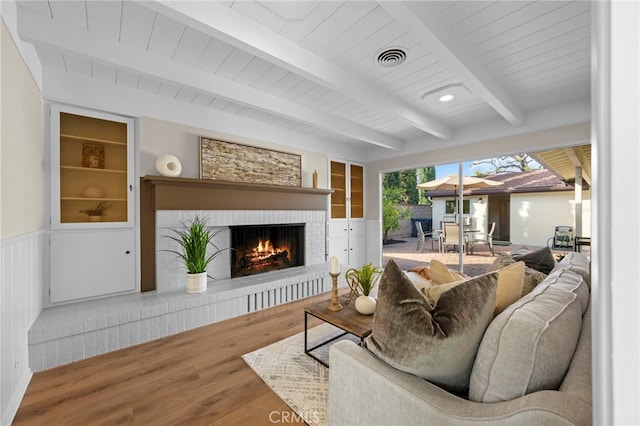 living room featuring built in features, wood-type flooring, a fireplace, wooden ceiling, and beamed ceiling