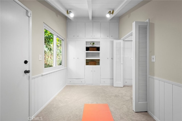 interior space featuring light carpet and beam ceiling