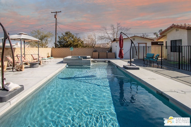 pool at dusk featuring an outdoor structure, a patio, and an in ground hot tub