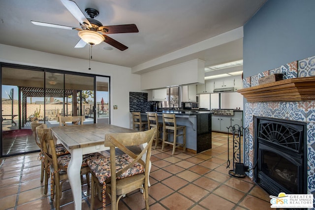 tiled dining space with a fireplace and ceiling fan