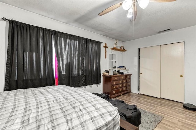 bedroom featuring ceiling fan, light hardwood / wood-style flooring, a closet, and a textured ceiling