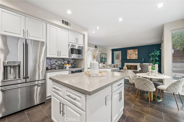 kitchen featuring white cabinetry, appliances with stainless steel finishes, decorative backsplash, and a wealth of natural light