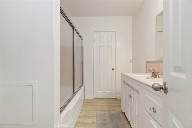 bathroom with vanity, hardwood / wood-style flooring, and enclosed tub / shower combo