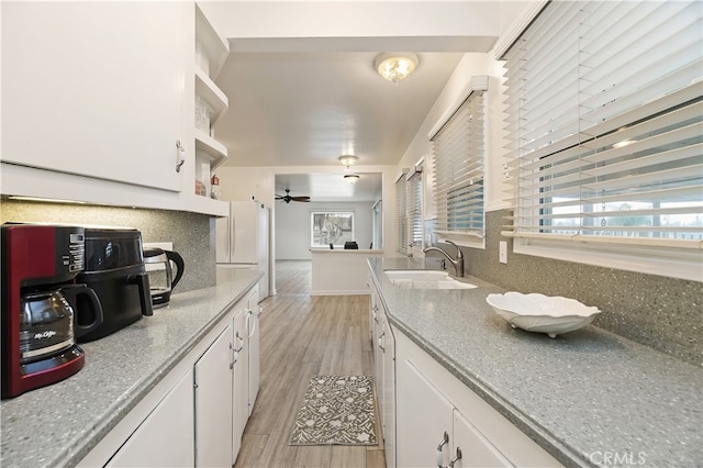 kitchen featuring white cabinetry, sink, backsplash, and light hardwood / wood-style floors