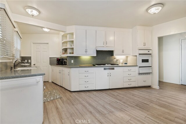 kitchen with tasteful backsplash, sink, oven, and white cabinets