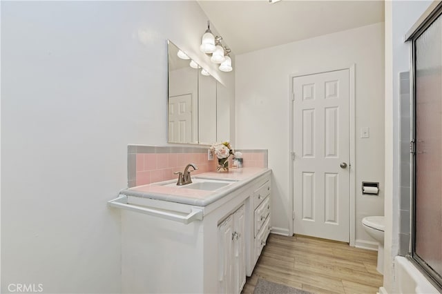 bathroom featuring wood-type flooring, vanity, backsplash, and toilet