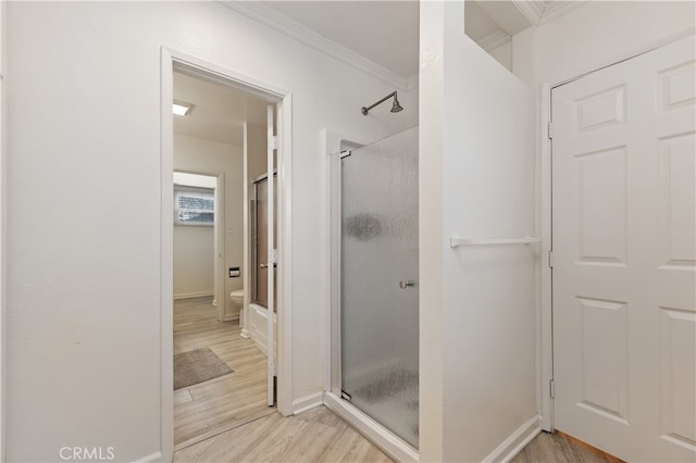 bathroom with crown molding, plus walk in shower, toilet, and hardwood / wood-style flooring