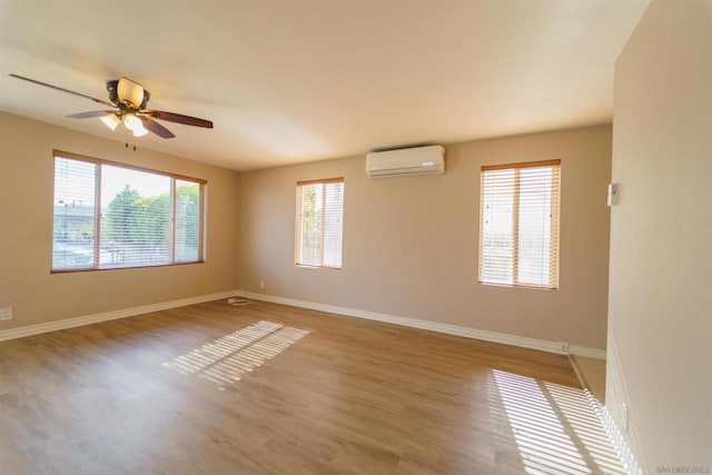 empty room with an AC wall unit, hardwood / wood-style floors, and ceiling fan