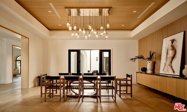 dining area with wood ceiling, light parquet flooring, a raised ceiling, and an inviting chandelier