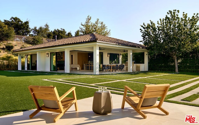 back of property featuring a yard, ceiling fan, and a patio area