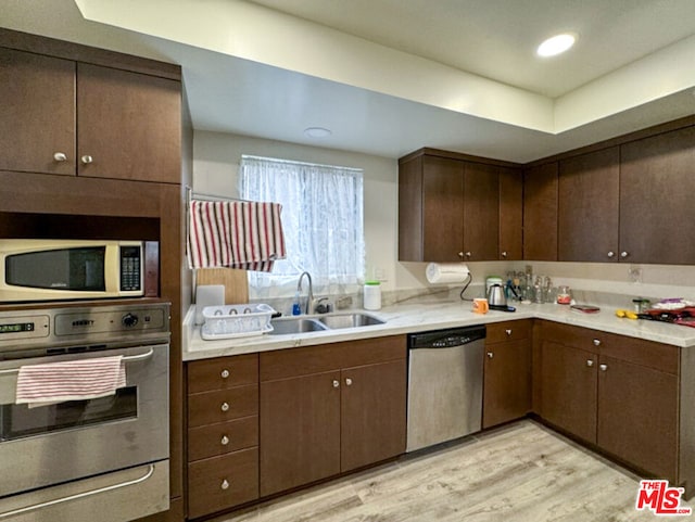 kitchen with dishwasher, dark brown cabinets, sink, and light hardwood / wood-style floors