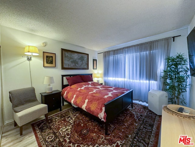 bedroom with wood-type flooring and a textured ceiling