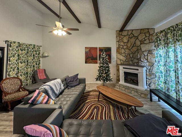 living room with lofted ceiling with beams, a textured ceiling, light hardwood / wood-style flooring, ceiling fan, and a fireplace