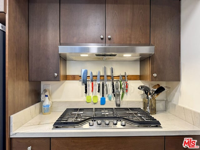 kitchen featuring light stone counters, dark brown cabinetry, and stainless steel gas cooktop