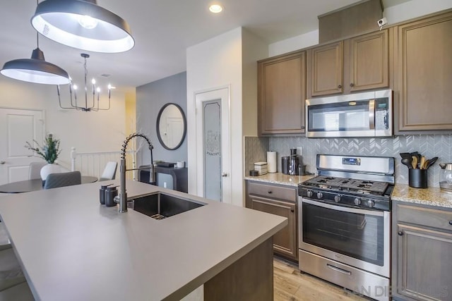 kitchen with stainless steel appliances, sink, an island with sink, and backsplash