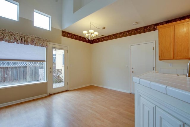 kitchen featuring an inviting chandelier, tile countertops, and light wood-type flooring