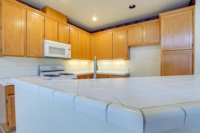 kitchen with tile countertops, white appliances, and kitchen peninsula