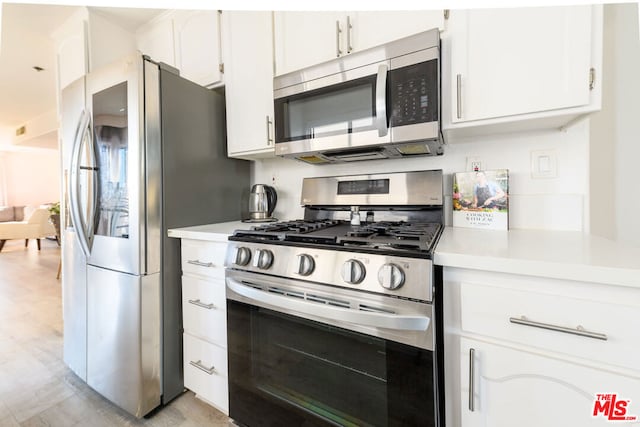 kitchen with white cabinetry, stainless steel appliances, and light wood-type flooring