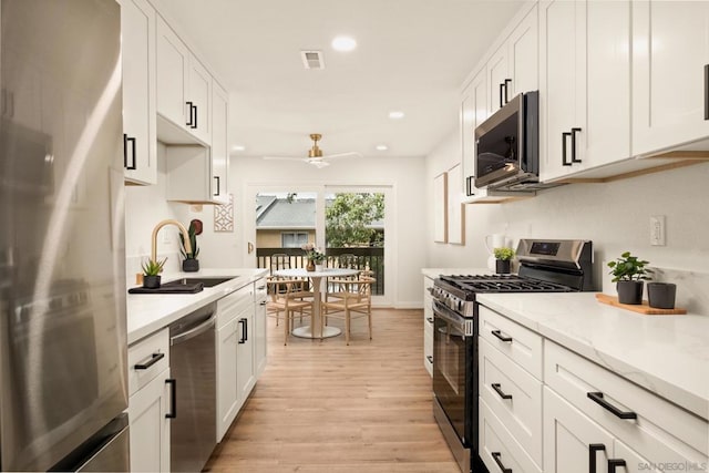 kitchen featuring sink, ceiling fan, appliances with stainless steel finishes, light hardwood / wood-style floors, and white cabinets