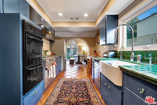 kitchen featuring tasteful backsplash, sink, dark tile patterned flooring, ornamental molding, and stainless steel appliances