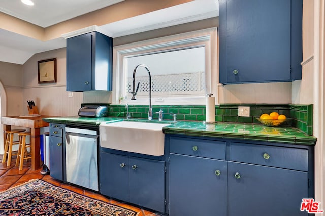 kitchen with tile countertops, blue cabinets, tasteful backsplash, sink, and stainless steel dishwasher