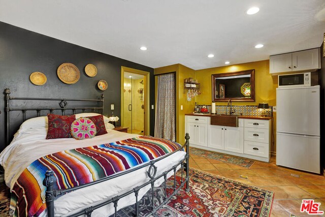 bedroom with light tile patterned floors, wet bar, and white refrigerator