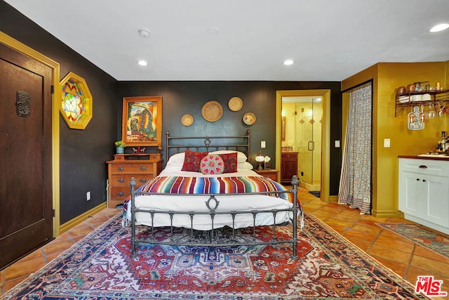 bedroom with ensuite bathroom and light tile patterned flooring