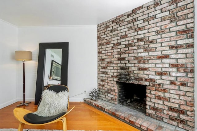 sitting room featuring a brick fireplace, hardwood / wood-style flooring, and ornamental molding