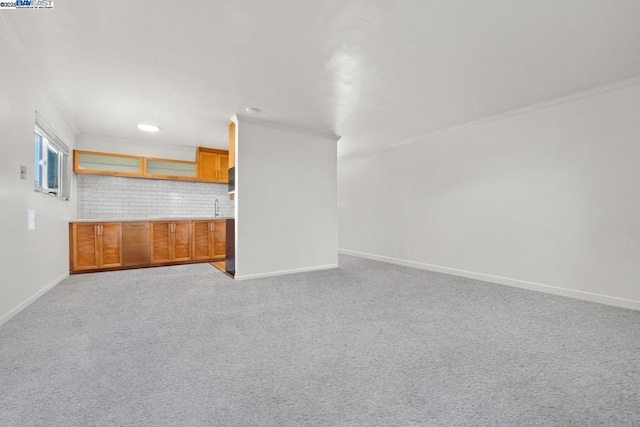 unfurnished living room featuring crown molding, sink, and light colored carpet