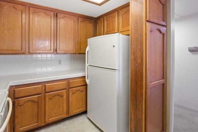 kitchen with tasteful backsplash, tile countertops, range, and white fridge