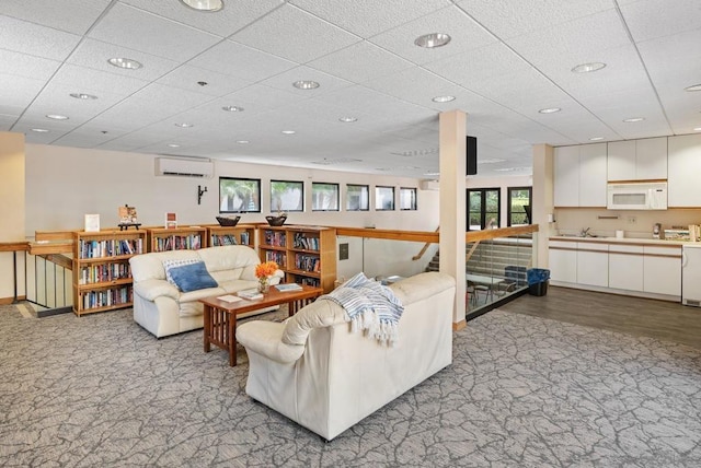 living room with a paneled ceiling, sink, light carpet, and an AC wall unit