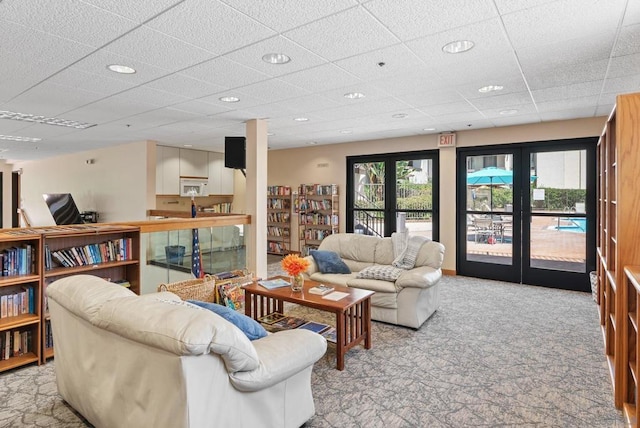 carpeted living room with french doors, plenty of natural light, and a drop ceiling