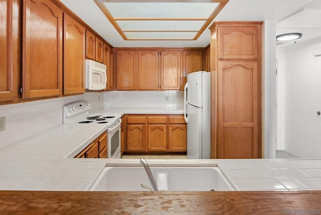 kitchen with tasteful backsplash, sink, tile counters, and white appliances