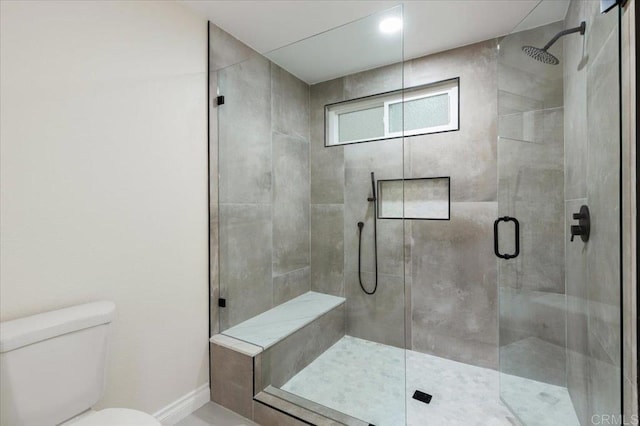 bathroom featuring a shower with door and toilet