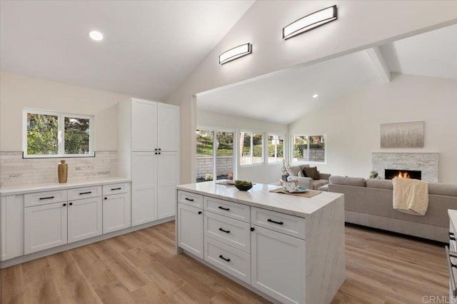 kitchen featuring lofted ceiling with beams, white cabinetry, a kitchen island, and light wood-type flooring