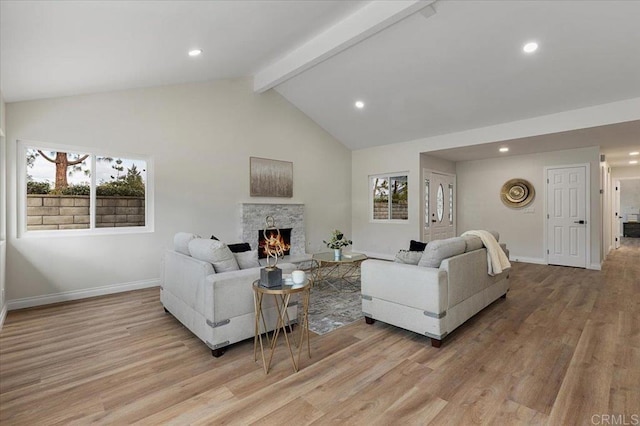 living room with vaulted ceiling with beams, a fireplace, and light wood-type flooring