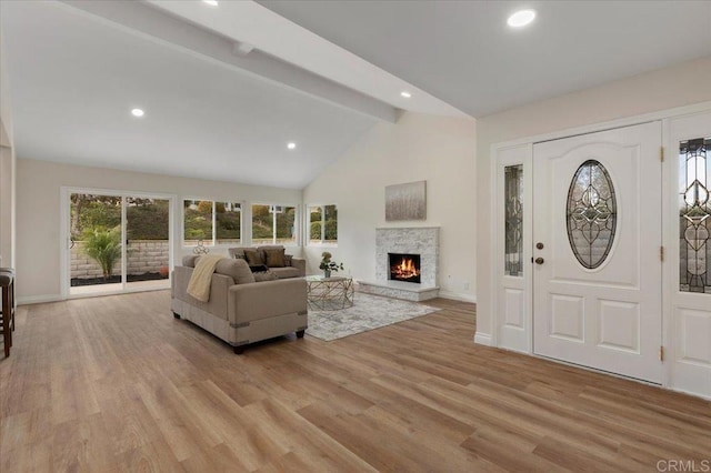 foyer featuring high vaulted ceiling, a fireplace, beam ceiling, and light hardwood / wood-style floors