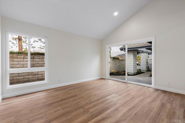 empty room featuring a healthy amount of sunlight, high vaulted ceiling, and wood-type flooring