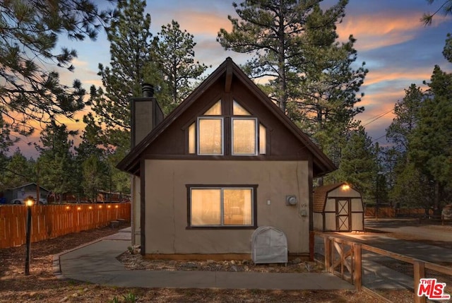 back house at dusk with a storage shed