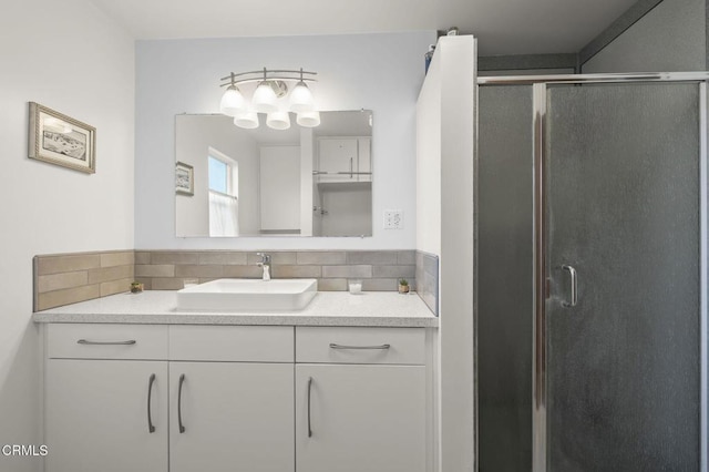 bathroom with vanity, a shower with door, and backsplash