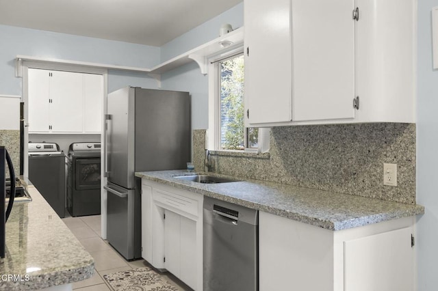 kitchen featuring light tile patterned floors, appliances with stainless steel finishes, white cabinetry, backsplash, and washing machine and dryer