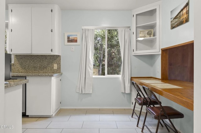 kitchen with white cabinetry, built in desk, and light stone countertops