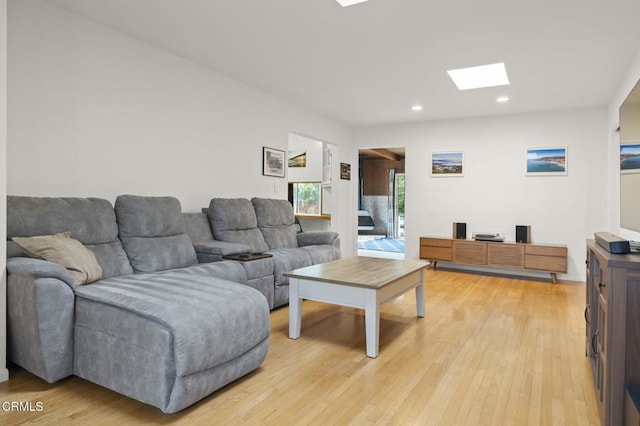 living room with light wood-type flooring and a skylight