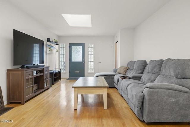 living room with light hardwood / wood-style floors and a skylight