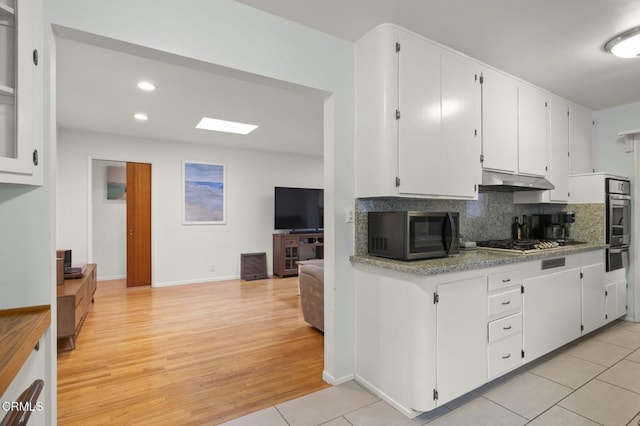 kitchen with white cabinetry, appliances with stainless steel finishes, light tile patterned flooring, and decorative backsplash