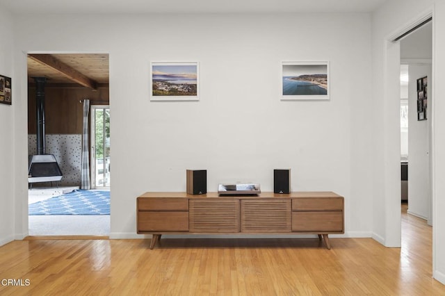 interior space featuring hardwood / wood-style flooring, wood ceiling, beam ceiling, and a wood stove