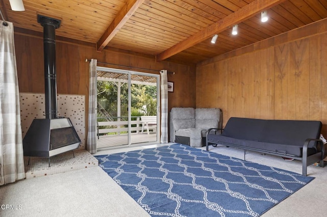 living area featuring wood ceiling, beam ceiling, wooden walls, carpet floors, and a wood stove