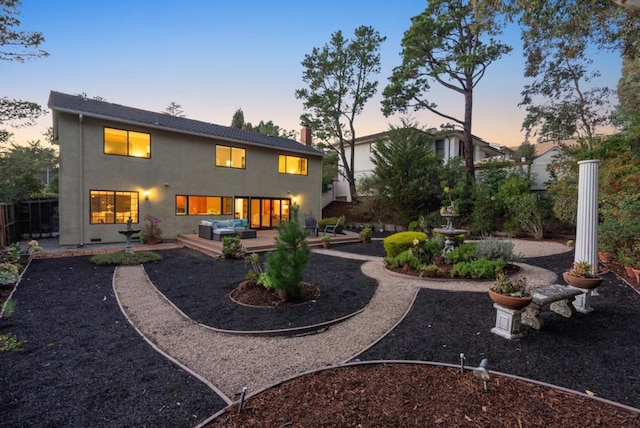 back house at dusk featuring outdoor lounge area and a patio